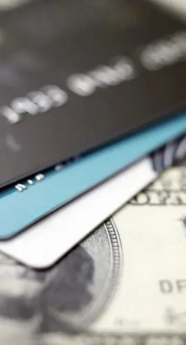 A close-up of credit cards placed on top of US currency bills.