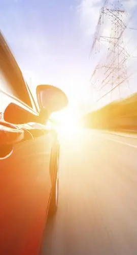A red car is speeding down a road, with a blurred background indicating high speed and motion.
