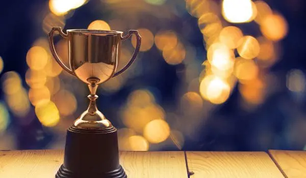 A trophy sits on a wooden surface against a blurred background of lights.